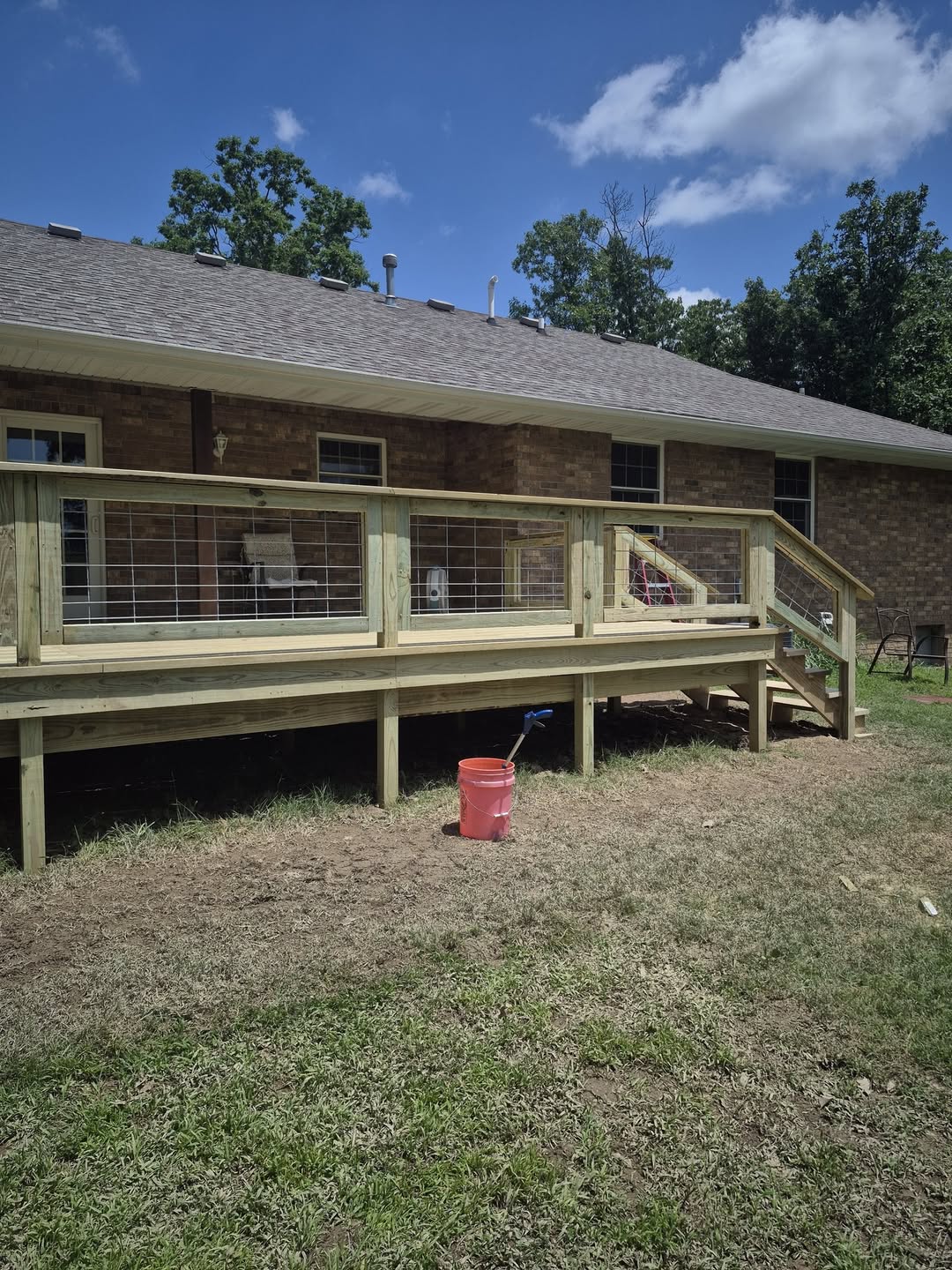 Raised deck and staircase completed beside a wooded home